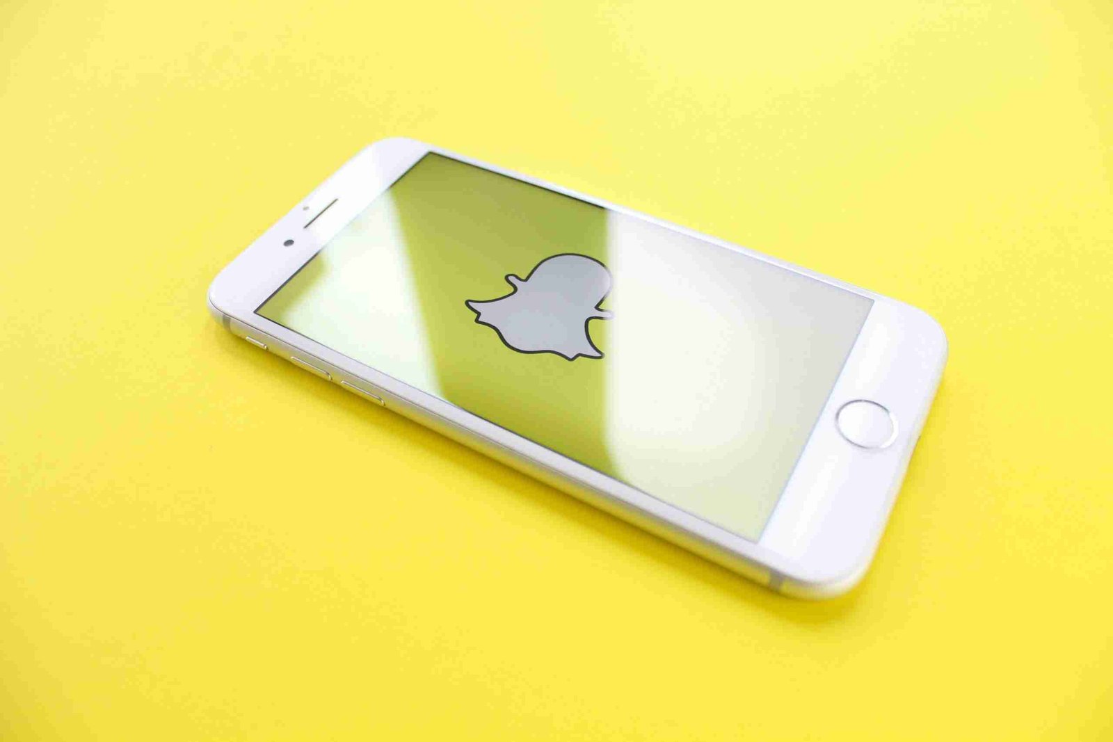Smartphone displaying Snapchat logo on a yellow background, highlighting vertical video marketing strategies for brand engagement in 2025.